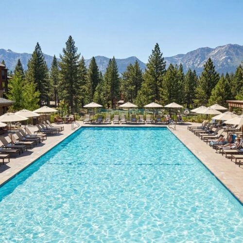 A large outdoor resort swimming pool surrounded by lounge chairs and mountain views.